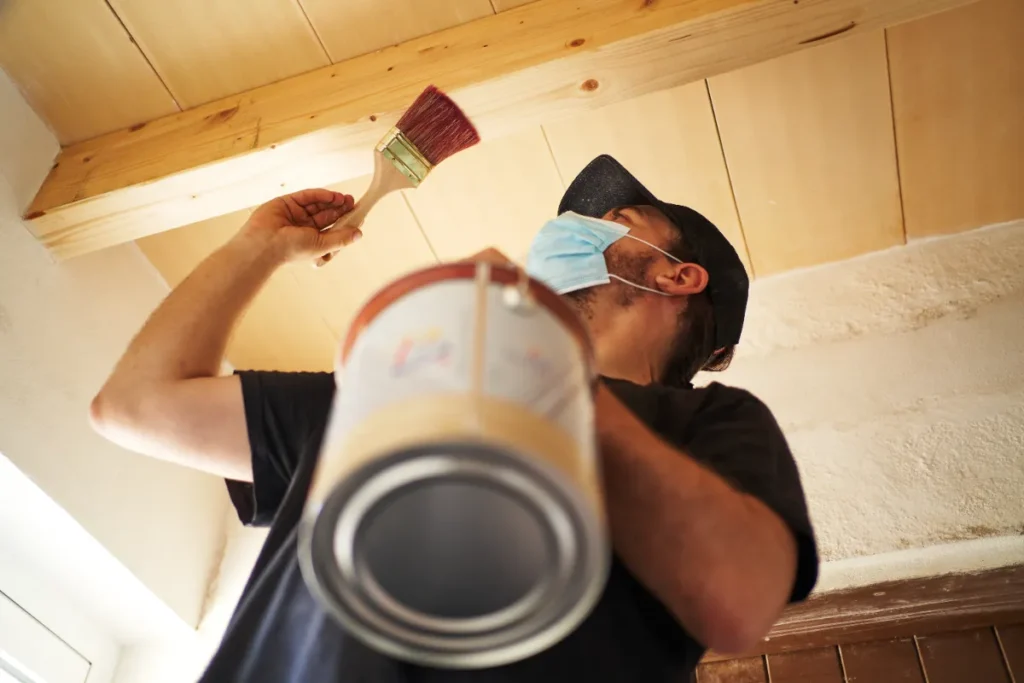 A worker painting the ceiling of the house.