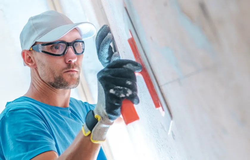 A worker leveling the walls with drywall paint.